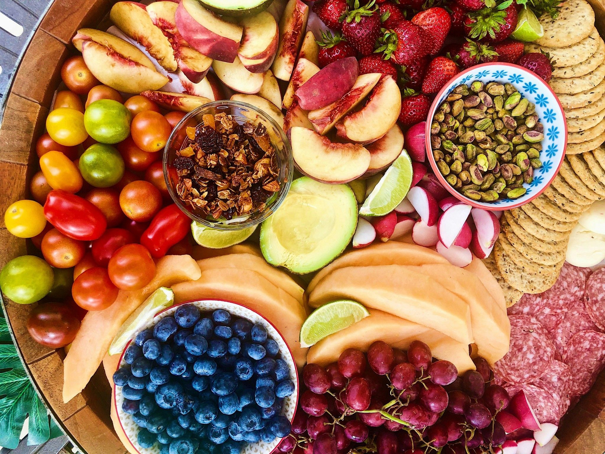 Overhead photograph of fruit, nuts, crackers and other snacks on a platter.